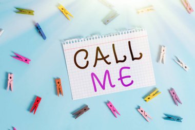 Call Me 'yi gösteren bir not yazıyorum. İş fotoğraflarının gösterildiği bir şey hakkında konuşmak için telefonla iletişim kurma isteği Renkli çamaşır iğnesi şeklinde dikdörtgen şeklinde kağıt mavi zemin.