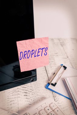 Metin işareti damlacıkları gösteriyor. Bir sıvının çok küçük bir damlası belirli ıslak yerlerde bulunabilir. Not kağıdı klavye ve durağan yakınlarındaki siyah bilgisayar ekranına bantlanmış..