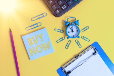 Buy Now 'u gösteren bir not yazıyorum. İş fotoğrafı gösterimi, birinden ürününüzü satın almasını istemek, iyi bir İndirimli Alarm saati pano, kalem hesap makinesi, renkli arkaplan....