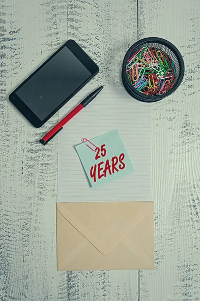 Текст текста 25 лет. Бизнес-концепция для памяти или чествования особого дня за 25 лет существования Смартфон скрепки бумаги держатель ручка конверт записка деревянный фон . — стоковое фото