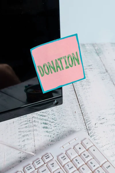 Writing note showing Donation. Business photo showcasing something that is given to a charity, especially a sum of money Note paper taped to black computer screen near keyboard and stationary.