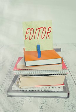 El yazısı yazı düzenleyicisi. Kavram demek, kimin sorumlu olduğunu göstermek ve dizilmiş kitap yığınının son içeriğini belirlemek demektir. Defter mandalı renkli hatırlatıcı beyaz ahşap..