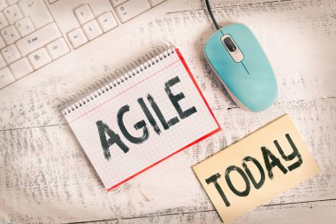 Agile 'i gösteren bir not yazıyorum. Proje yönetimine özel bir yaklaşım sergileyen iş fotoğrafı, yazılım yazma ekipmanları ve tahta masaya yerleştirilen bilgisayar malzemelerinde kullanılıyor..