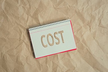Cost 'u gösteren kavramsal el yazısı. Ticari fotoğraf sergisi. Satın aldığınız bir ürün için ödediğiniz para ya da bir gösteri masası sarmal defter ofis malzemesi..
