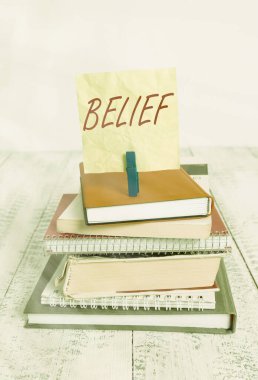Handwriting text writing Belief. Concept meaning the feeling of being certain that something exists or is true pile stacked books notebook pin clothespin colored reminder white wooden. clipart