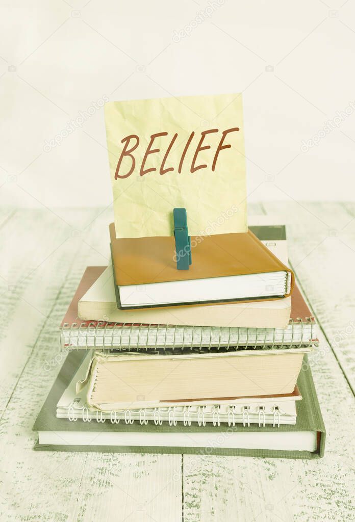Handwriting text writing Belief. Concept meaning the feeling of being certain that something exists or is true pile stacked books notebook pin clothespin colored reminder white wooden.