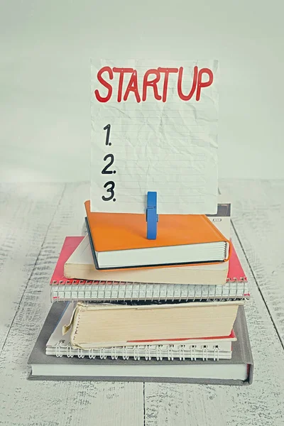 Writing note showing Startup. Business photo showcasing the action of setting something in motion newly established business pile stacked books notebook pin color reminder white wooden. — Stock Photo, Image