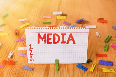 Medya 'yı gösteren kavramsal el yazısı. Toplu iletişimin ana araçlarını gösteren bir iş fotoğrafı. Toplu olarak kabul edilen renkli buruşmuş kağıtlar. Ahşap zemin, çamaşır mandalı..