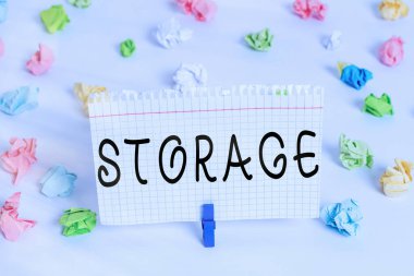 Depoyu gösteren mesaj işareti. Kavramsal fotoğraf depolama eylemi gelecekteki kullanım için bir şeyler güvenli tutun Renkli buruşmuş kağıtlar boş hatırlatıcı beyaz zemin çamaşır mandalı.