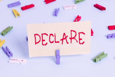 Deklare 'i gösteren kavramsal el yazısı. Ticari fotoğraf sergisi, özellikle açık ve resmi terimlerle özellikle renkli çamaşır tokası boş hatırlatıcı mavi zemin ofisini gösterir..