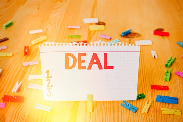 Conceptuele handschrift tonen Deal. Zakelijke foto showcasing Neem deel aan de commerciële handel van een bepaald product Wees betrokken bij gekleurde verkreukelde papieren houten vloer achtergrond wasknijper. — Stockfoto