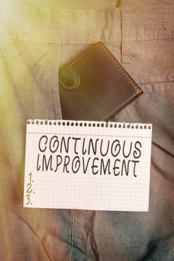 Devamlı gelişmeyi gösteren kavramsal el yazısı. İş fotoğrafı metni İlerlemeye Devam Ediyor Hiç Bitmeyen, gösterim kağıdının yanındaki pantolon cebindeki küçük cüzdanı değiştirir.