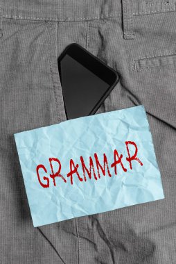 Text sign showing Grammar. Conceptual photo whole system and structure of a language or of languages in general Smartphone device inside formal work trousers front pocket near note paper. clipart