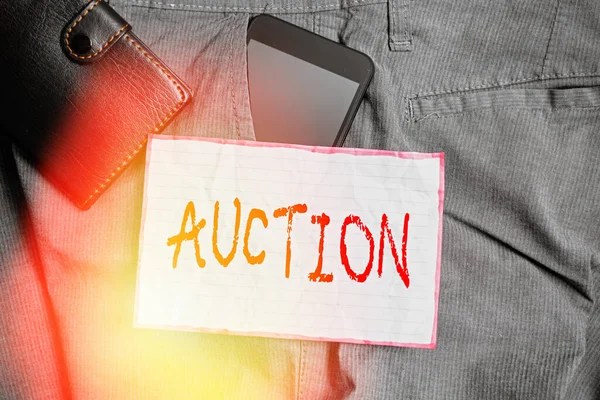 Text sign showing Auction. Conceptual photo Public sale Goods or Property sold to highest bidder Purchase Smartphone device inside trousers front pocket with wallet and note paper.