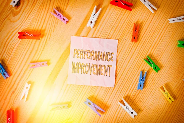 Word writing text Performance Improvement. Business concept for Measure and Modify the Output to increase efficiency Colored clothespin papers empty reminder wooden floor background office.