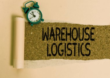 Depo Lojistik 'i gösteren bir not yazıyorum. İş dünyasındaki hem fiziksel malların hem de bilgilerin akışını gösteren bir iş fotoğrafı. Alarm saati ve yırtık bir karton kutu. Klasik bir masa arkaplanı..