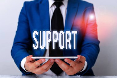 Kelime yazma desteği. Katılıyor ve teşvik ediyor. Mavi süitte dizüstü bilgisayarı elinde tutan bir iş adamı..