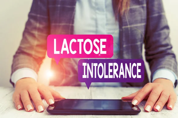 Word writing text Lactose Intolerance. Business concept for digestive problem where body is unable to digest lactose Business woman sitting with mobile phone on the table.