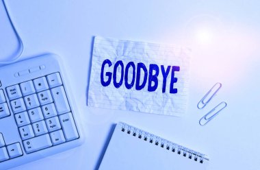 Handwriting text Goodbye. Concept meaning used to express good wishes when parting or end of a conversation White pc keyboard with empty note paper above white background.