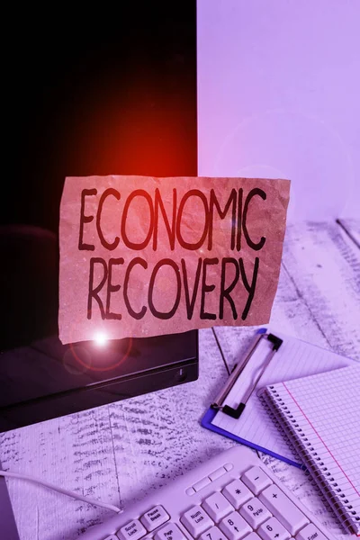 Conceptual hand writing showing Economic Recovery. Business photo showcasing rise of business activity signaling the end of a recession Note paper taped to black screen near keyboard stationary. — Stock Photo, Image