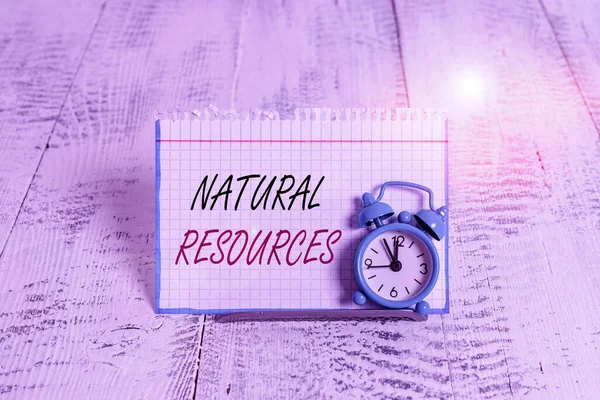 Word writing text Natural Resources. Geschäftskonzept für Materialien, die in der Natur vorkommen und für wirtschaftlichen Gewinn verwendet werden Mini-blauer Wecker steht über Pufferdraht vor Notizblock gekippt. — Stockfoto