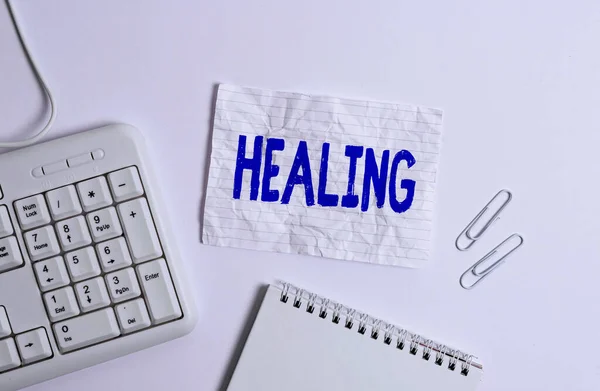 Handwriting text Healing. Concept meaning process of making or becoming sound or healthy again Helping injured White pc keyboard with empty note paper above white background. — Stok fotoğraf