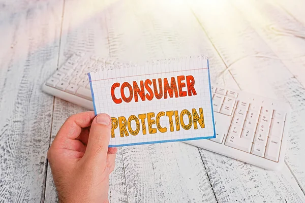 Text sign showing Consumer Protection. Conceptual photo Fair Trade Laws to ensure Consumers Rights Protection man holding colorful reminder square shaped paper white keyboard wood floor. — Stock Photo, Image