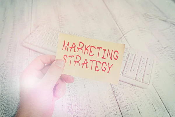 Conceptual hand writing showing Marketing Strategy. Business photo text Scheme on How to Lay out Products Services Business Man holding colorful reminder square shaped paper wood floor. — Stock Photo, Image