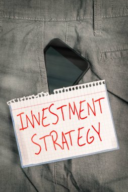 Yatırım Stratejisini gösteren bir not yazıyorum. İş fotoğraflarının gösterimi Kuralların İşlem Kümesi Bir Yatırımcı Akıllı Telefon Rehberi Davranışı Pantolonun ön cebinde.