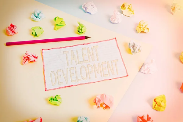 Conceptual hand writing showing Talent Development. Business photo text Building Skills Abilities Improving Potential Leader Colored crumpled papers empty reminder blue yellow clothespin.