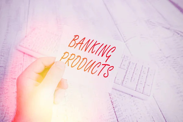 Word writing text Banking Products. Business concept for safe and convenient way or service to accumulate savings man holding colorful reminder square shaped paper white keyboard wood floor.