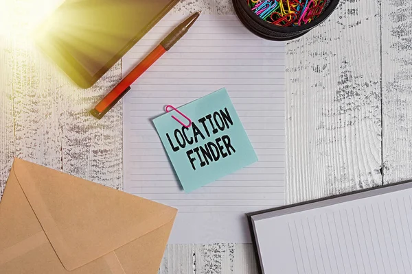 Text sign showing Location Finder. Conceptual photo A service featured to find the address of a selected place Smartphone sheet clips ballpoint notebook envelope note wooden background.