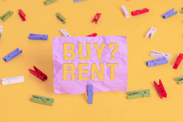 Word writing text Buy Question Rent. Business concept for Group that gives information about renting houses Colored clothespin papers empty reminder yellow floor background office.