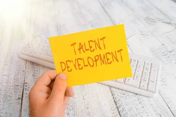 Conceptual hand writing showing Talent Development. Business photo showcasing Building Skills Abilities Improving Potential Leader Man holding colorful reminder square shaped paper wood floor.