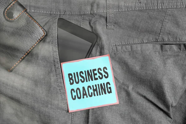 Word writing text Business Coaching. Business concept for Helping employees become more active Consulting an expert Smartphone device inside trousers front pocket with wallet and note paper.
