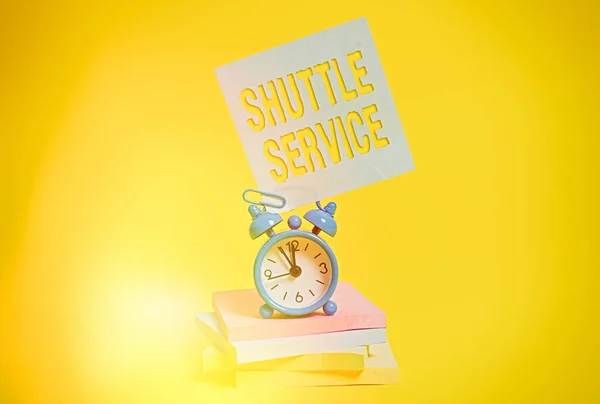 Word writing text Shuttle Service. Business concept for vehicles like buses travel frequently between two places Metal alarm clock blank sticky note stacked notepads colored background.