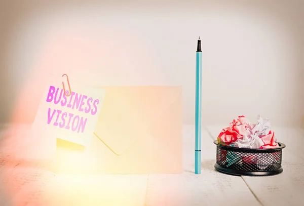 Writing note showing Business Vision. Business photo showcasing grow your business in the future based on your goals Envelope sticky note marker paper balls container wooden background.
