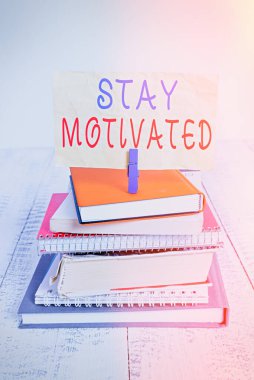 Text sign showing Stay Motivated. Conceptual photo Reward yourself every time you reach a goal with knowledge pile stacked books notebook pin clothespin colored reminder white wooden. clipart