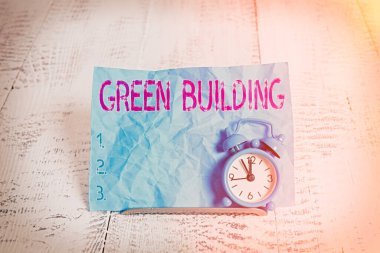 Yeşil Bina 'yı gösteren mesaj işareti. Kavramsal fotoğraf. Çevreye duyarlı bir yapı. Sürdürülebilir Mini mavi alarm saati..