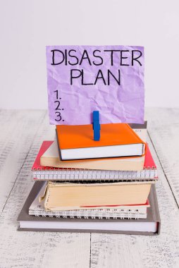 El yazısı Felaket Planı. Kavram, acil durum hazırlıklarına cevap ver demek. Hayatta kalma ve ilk yardım çantası yığını. Defter, çamaşır mandalı, hatırlatıcı beyaz ahşap..