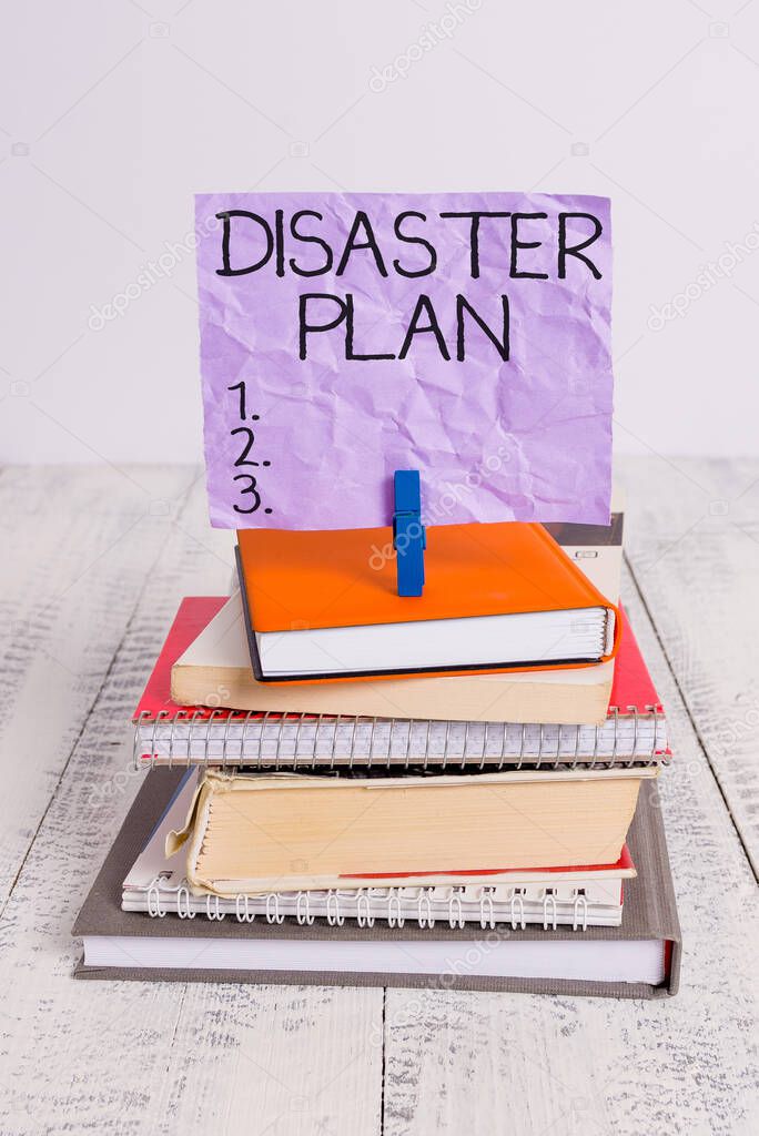 Handwriting text Disaster Plan. Concept meaning Respond to Emergency Preparedness Survival and First Aid Kit pile stacked books notebook pin clothespin colored reminder white wooden.
