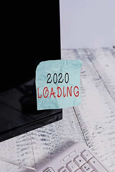Text sign showing 2020 Loading. Conceptual photo Advertising the upcoming year Forecasting the future event Notation paper taped to black computer monitor screen near white keyboard.