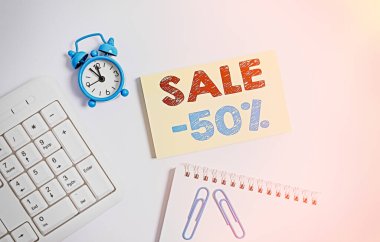 % 50 indirim gösteren bir not yazıyorum. İş fotoğrafı gösterimi% 50 indirimli bir nesnenin promosyon fiyatı boş kağıt ve kalem beyaz arkaplan ile klavye.