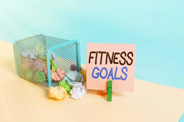 Writing note showing Fitness Goals. Business photo showcasing Loose fat Build muscle Getting stronger Conditioning Trash bin crumpled paper clothespin reminder office supplies.