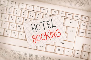 Otel rezervasyonunu gösteren bir not yazıyorum. Çevrimiçi rezervasyonları gösteren iş fotoğrafı Başkanlık Süiti De Luxe Misafirperverlik Klavye Ofisi dikdörtgen şekilli kağıt, ahşap.