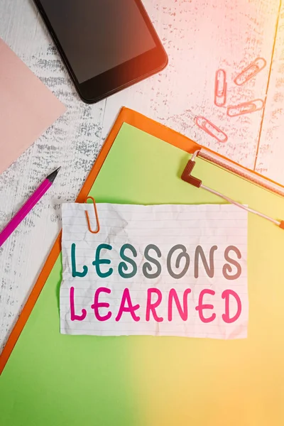Text sign showing Lessons Learned. Conceptual photo information reflects positive and negative experiences Clipboard sheet pencil smartphone note clips notepad wooden background. — Stock Photo, Image