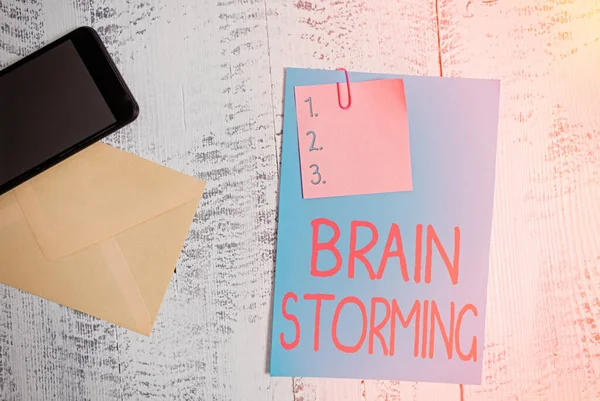 Text sign showing Brain Storming. Conceptual photo Stimulating creative thinking Developing new ideas Discussion Envelope blank sheet paper sticky note smartphone wooden vintage background.