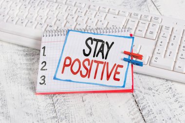 Metin işareti pozitif kal diyor. Düşünceleri canlandıran kavramsal fotoğraf İyimser ve Gerçek Defter Kağıdı hatırlatıcısı Mandallı çarşaf, beyaz klavye ışığı ahşap.