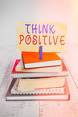 Mesaj işareti olumlu düşün diyor. Kavramsal fotoğraf. Olumlu ya da iyimser olma eğilimi. Yığınla kitap yığını..