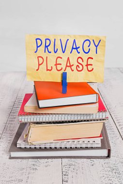Mahremiyeti gösteren metin işareti. Lütfen. Kavramsal fotoğraf, birinden kişisel alanınıza saygı göstermesini istemektir. Yığınla kitap yığınını bırakın. Defter mandalı renkli hatırlatıcı beyaz ahşap..